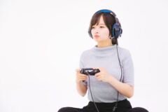 ヘッドフォンを付けコントローラーを持ってゲームで遊ぶ女性