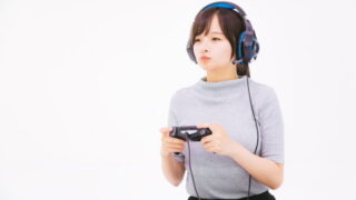 ヘッドフォンを付けコントローラーを持ってゲームで遊ぶ女性
