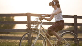 VRヘッドギアを付けて自転車に乗る女性